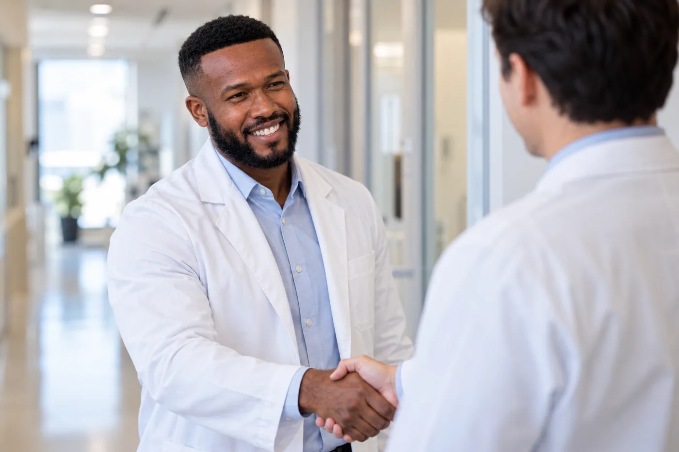 Dr. Peter K. Cudjoe shaking hands with another clinician in a clinic corridor